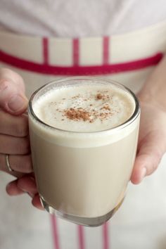 a person holding a drink in their hand with cinnamon sprinkles on top