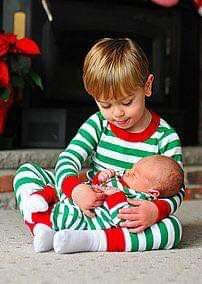 a little boy sitting on the ground holding a baby