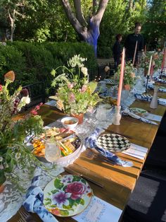 a long table with plates and flowers on it is set for an outdoor dinner party