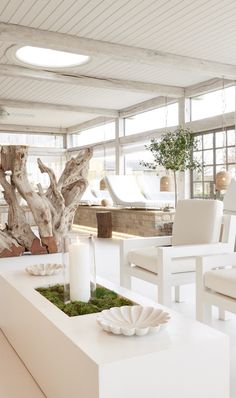 a living room filled with white furniture and a planter on top of a table