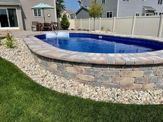 a backyard with a pool surrounded by rocks and grass