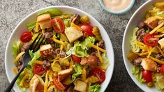 two white bowls filled with salad and dressing on top of a marble table next to a cup of mayonnaise