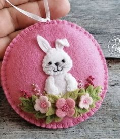 a hand holding a pink ornament with a white rabbit on it