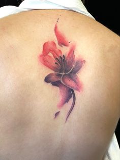 a woman's back with a flower tattoo on it