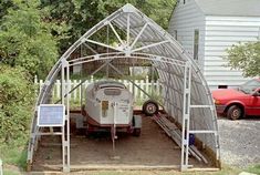 a car is parked in front of a metal structure with a boat on it's trailer