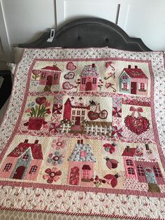 a quilted bed spread with houses and flowers on the bedspread is shown