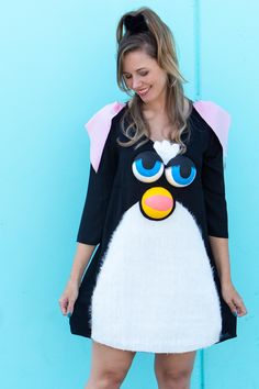 a woman standing in front of a blue wall wearing a black and white penguin costume