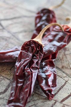 red peppers are sitting on the ground next to a wooden spoon