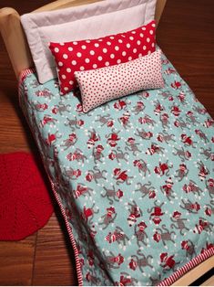 a bed with red and white polka dot pillows on top of it next to a wooden headboard