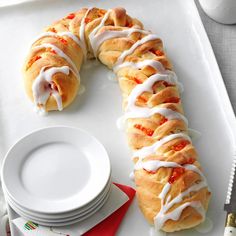 a white tray topped with a pastry covered in icing next to plates and utensils