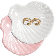 two gold - plated rings are placed on top of a pink seashell shell