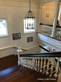 the stairs in this house have been painted white with black balconies and chandeliers