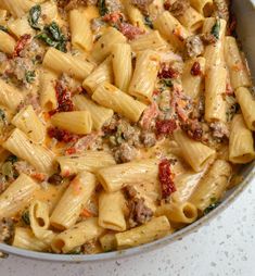 pasta with sausage and spinach in a pan on the stove top, ready to be cooked