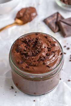 a glass jar filled with chocolate pudding next to two spoons