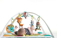 a baby laying on its back in front of a play gym with toys hanging from it's sides