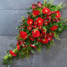 a bouquet of red flowers laying on top of a stone floor next to green leaves