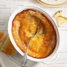 a close up of a casserole in a bowl with a spoon on a table