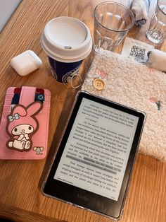 an electronic device sitting on top of a wooden table next to a cup of coffee