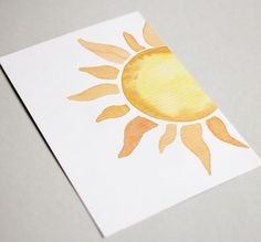 an orange and yellow sun painted on white paper with watercolor pencils in it