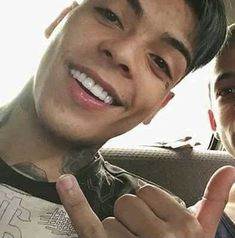 two young men are smiling and giving the thumbs up sign while sitting in a car