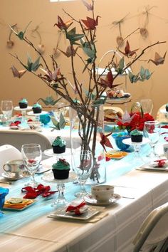 the table is set with many glasses, plates and flowers in vases on it