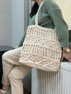 a woman is sitting on a radiator holding a crocheted tote bag