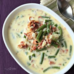 a bowl of soup with green beans and bacon in it on a purple place mat