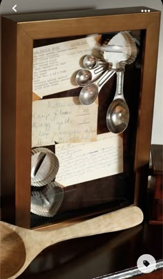 spoons and measuring spoons are in a shadow box with writing on the side