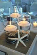 candles are arranged in glass bowls with rocks and starfish on the bottom, along with seashells