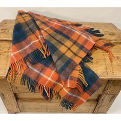 an orange and blue plaid blanket sitting on top of a wooden box