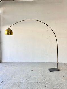 a floor lamp with a metal base and a gold shade on it's head