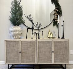 a large round mirror sitting on top of a wall next to a white cabinet and christmas decorations