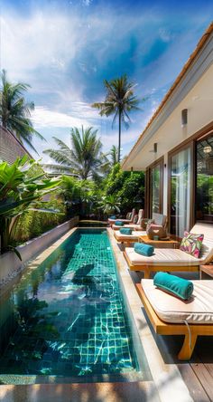 an outdoor swimming pool with chaise lounges next to it and palm trees in the background