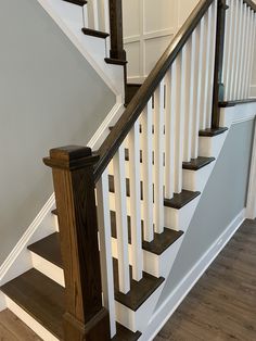 a white staircase with wooden handrails and wood flooring in a home setting