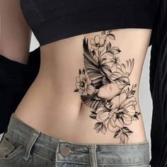 a woman's stomach with flowers and birds tattoo on her side ribcage