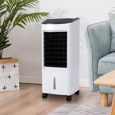 an air cooler sitting on top of a hard wood floor next to a chair and potted plant