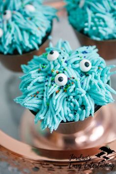 cupcakes decorated with blue frosting and sprinkles in the shape of monsters