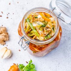 a glass jar filled with food next to some vegetables