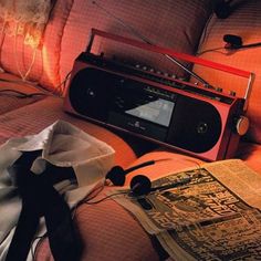 an old radio sitting on top of a bed next to pillows and a pillow with a black ribbon