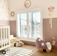 a baby's room with pink walls and white shutters