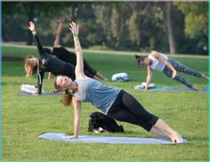 a group of people doing yoga in the park on their stomachs and arms together