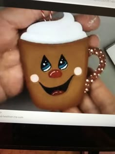 a person holding a coffee cup with a face painted on it's front and side