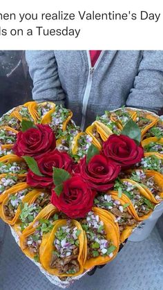 a heart shaped cake with red roses on top is held by a woman's hands