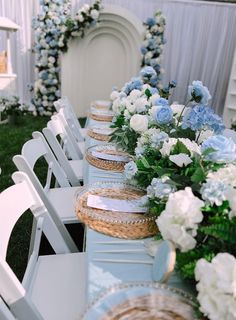 a long table with blue and white flowers on it is set up for an outdoor event