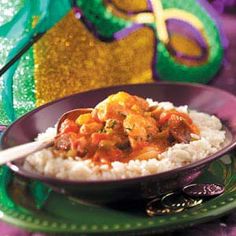 a plate with rice, meat and vegetables next to a mardi gras mask