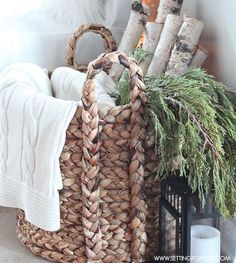 a basket filled with lots of different types of items next to a candle and blanket