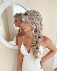 a woman with long hair in a wedding dress looking at her reflection in the mirror