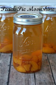 three mason jars filled with peaches sitting on top of a wooden table