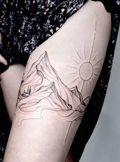 a woman's thigh with a mountain tattoo on it