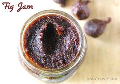 a jar filled with jam sitting on top of a wooden table next to raisins